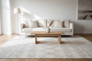 Neutral geometric area rug styled in a calm living room with cream sofa and wooden coffee table — Flatiron Home